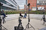 2 Personen bei einem Videodreh, umgeben von Kameraausrüstung 